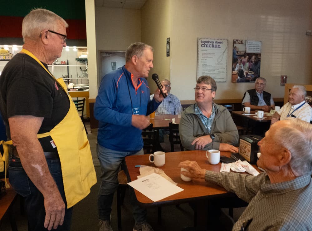 Club members listening to a standing speaker with a microphone.